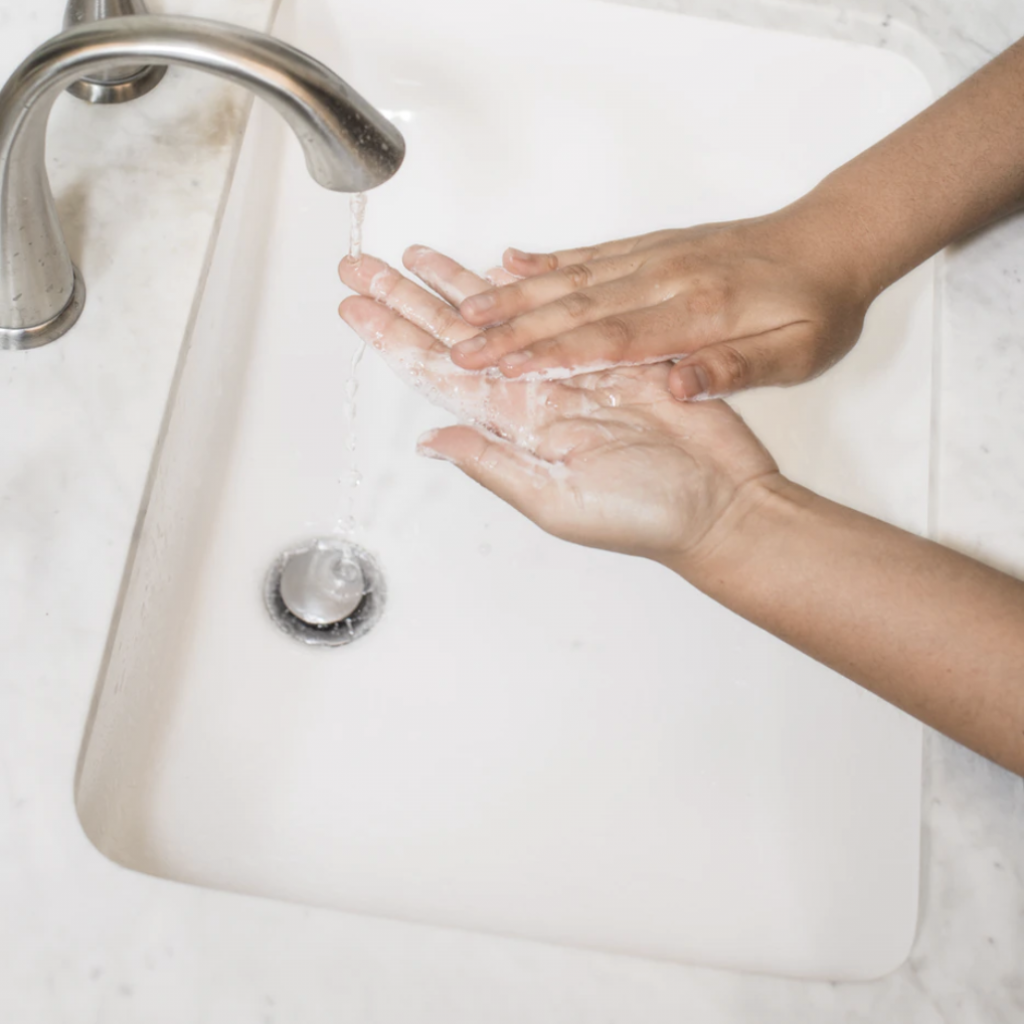 soap being rinsed off hands under a faucet 